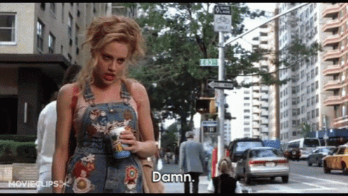 a woman in overalls is holding a cup of coffee and says " damn "