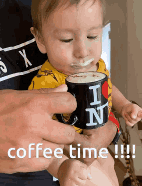 a baby is holding a mug that says i love ny