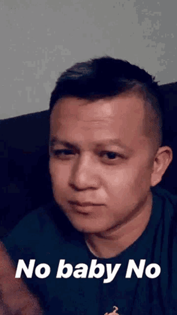 a man is sitting on a couch and making a funny face with the words no baby no on the bottom .
