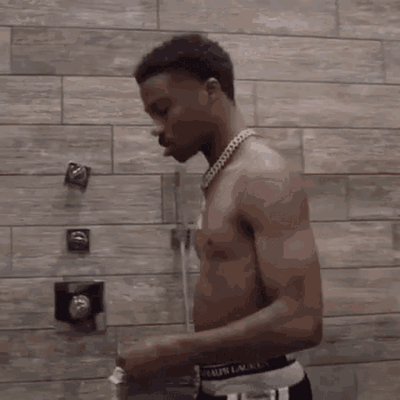 a shirtless man is standing in a bathroom with his arms outstretched .