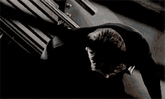 a man in a black shirt is laying on the ground with his head in his hands .