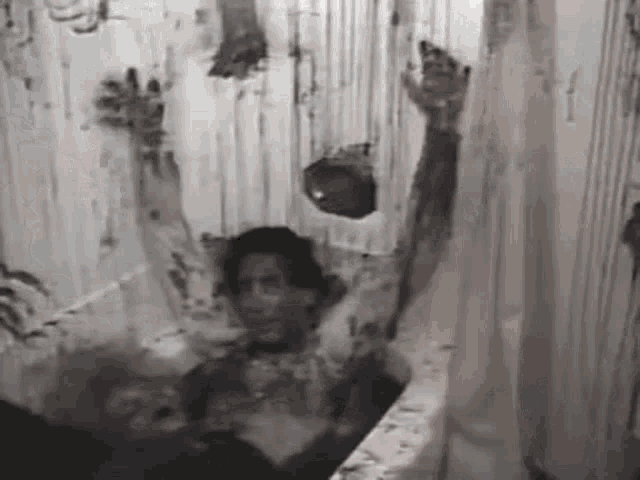 a black and white photo of a man laying in a bathtub with blood coming out of his head .