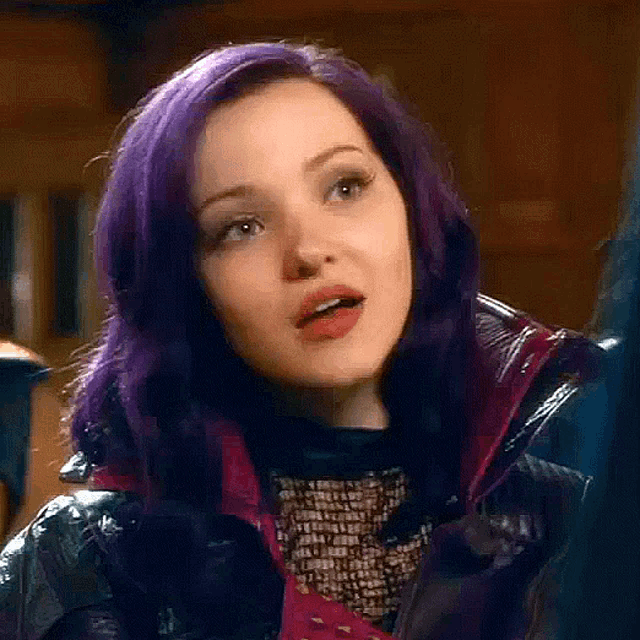 a close up of a woman with purple hair wearing a leather jacket and a black shirt .