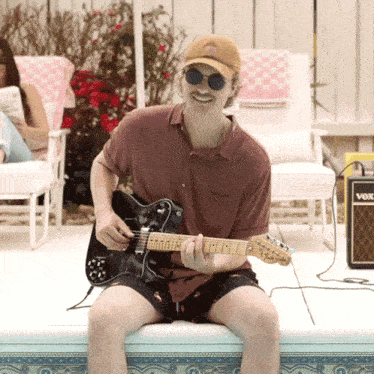 a man playing a guitar next to a vox amp