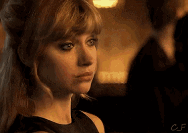 a woman in a black dress is looking at a man in a black suit .