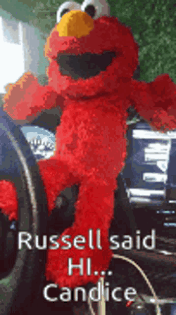 a elmo stuffed animal is sitting in the driver 's seat of a car and russell said hi candice