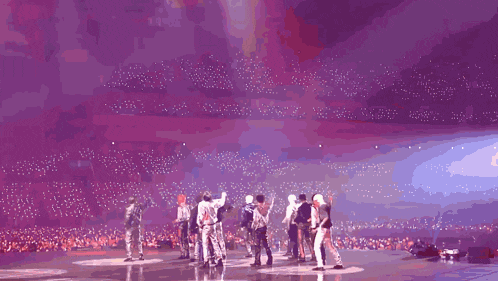 a group of people are standing on a stage with fireworks coming out of the ceiling .