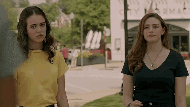 two girls are standing in front of a building that says city