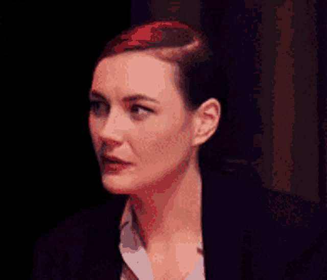a woman with red hair is wearing a black jacket and a white shirt