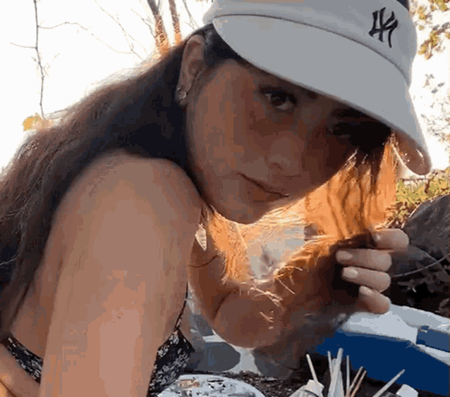 a woman wearing a hat and a bikini is holding a piece of food .