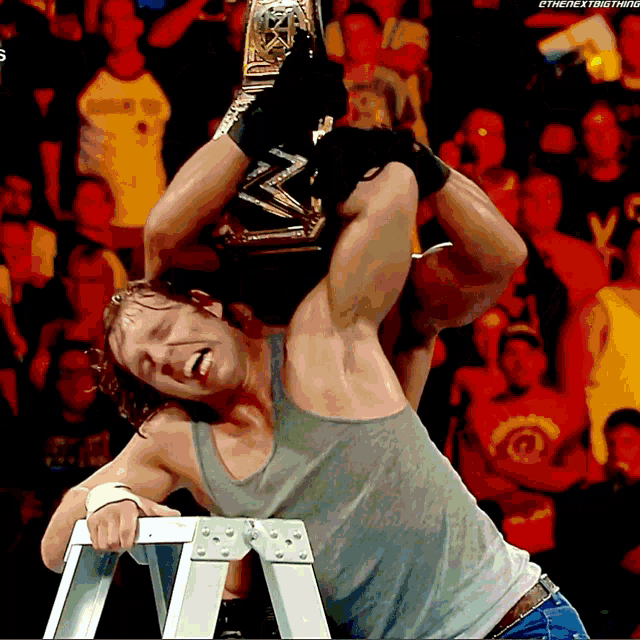 a wrestler holds a wwe championship belt over his head in front of a crowd