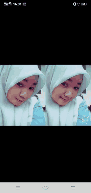 a girl wearing a white hijab is taking a selfie on her phone