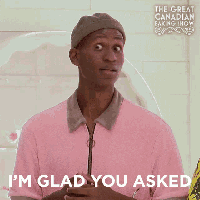 a man in a pink shirt says " i 'm glad you asked " in front of the great canadian baking show
