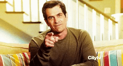 a man is pointing at the camera while sitting on a couch sponsored by citytv