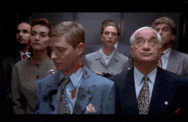 a group of people in suits and ties are standing in an elevator looking up