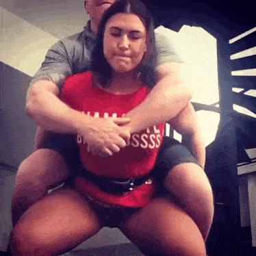 a man is carrying a woman on his back who is wearing a red shirt that says ' sss ' on it