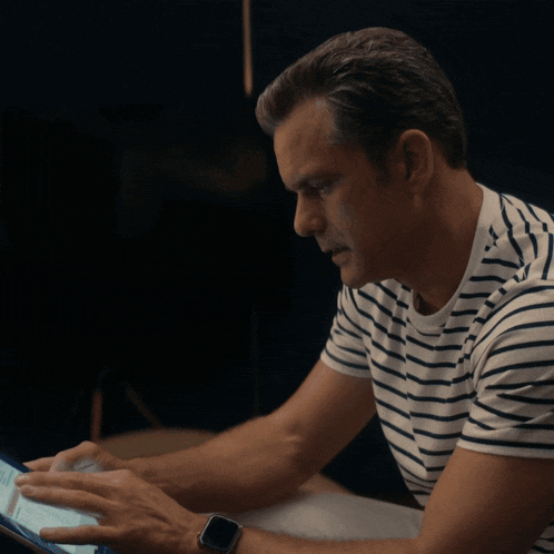 a man in a striped shirt is using a tablet computer