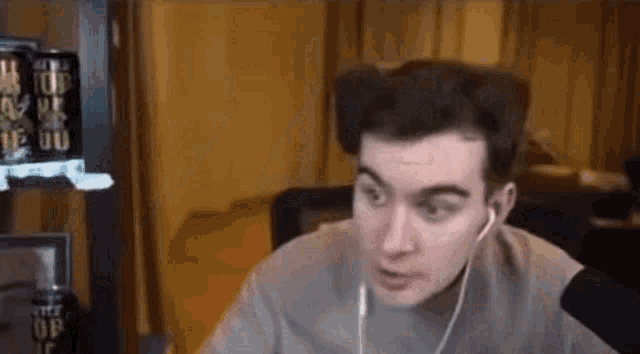 a man wearing earbuds is sitting in front of a microphone in a room .
