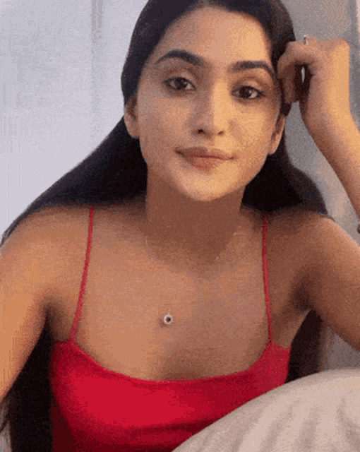 a woman wearing a red tank top and a necklace with an eye on it
