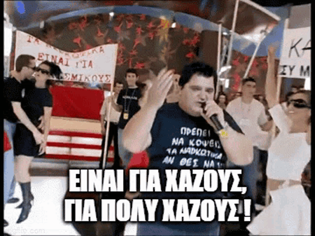 a man singing into a microphone while wearing a shirt that says einai