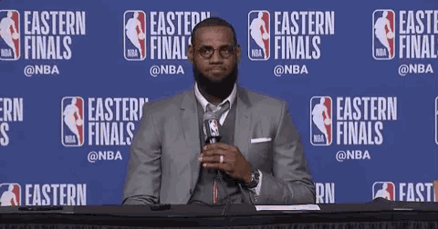 a man in a suit is sitting at a table with a microphone in front of a wall that says easter finals