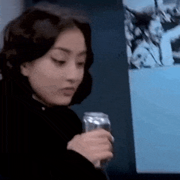 a woman is holding a can of soda in front of a painting .