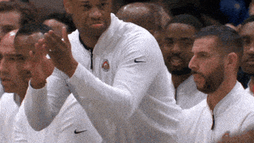 a man wearing a white nike jacket applauds his team