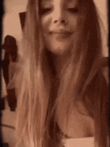 a woman with long blonde hair is smiling and looking at the camera .