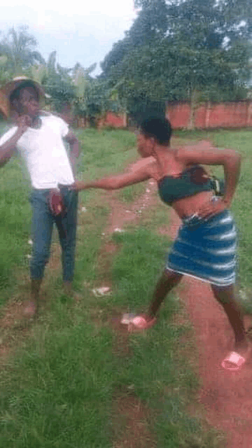 a man and a woman are standing in a field fighting each other .