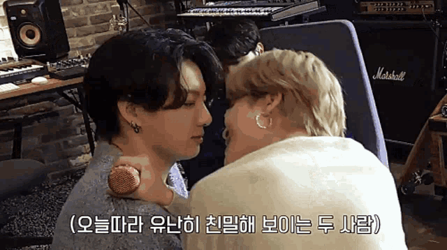 two men are kissing in front of a marshall amplifier .