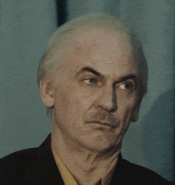 a man with white hair and a mustache is wearing a suit and a yellow shirt and making a funny face .
