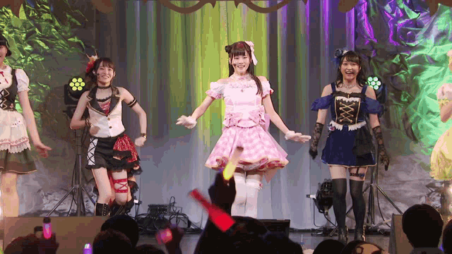 a group of girls are dancing on a stage and one of them is holding a red light stick