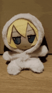 a stuffed animal with a yellow hair and blue eyes is sitting on the floor