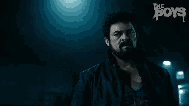 a man with a beard is standing in a dark room with the words the boys on the bottom