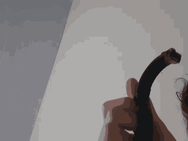 a person holding a black object in their hand against a white wall