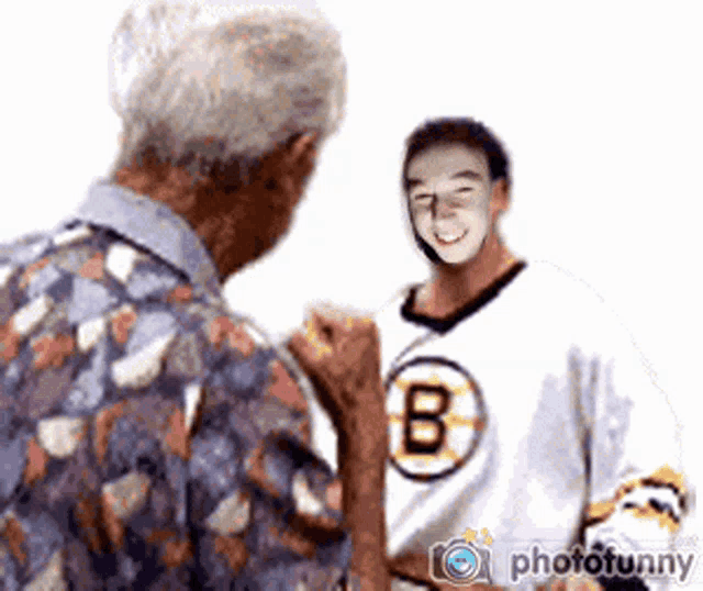 a man wearing a boston bruins jersey talks to an older man