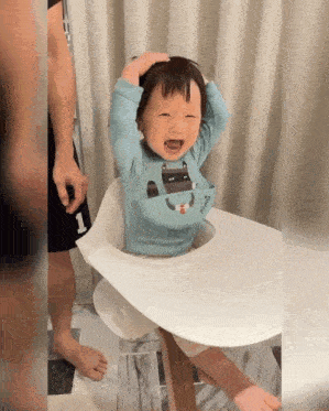 a baby sitting in a high chair with a bib on that says munchkin