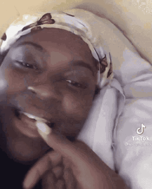 a woman is laying on a bed with a head scarf on her head .