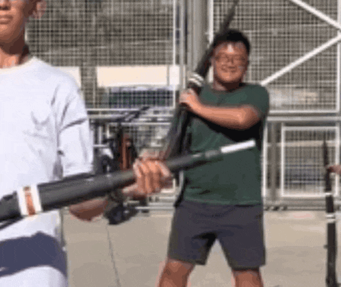a man in a green shirt is holding a sword while another man in a white shirt is holding a sword .