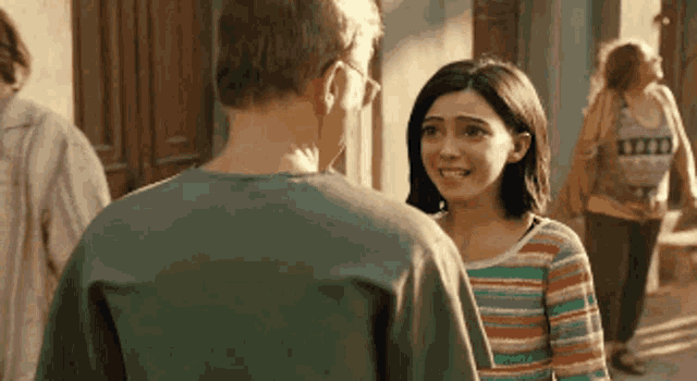 a man and a woman are standing next to each other on a street . the woman is wearing a striped shirt .