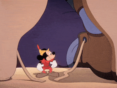 a cartoon of mickey mouse standing next to a giant boot