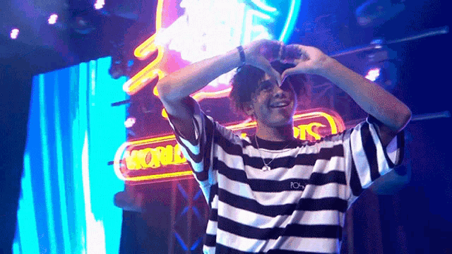 a man in a striped shirt making a heart shape
