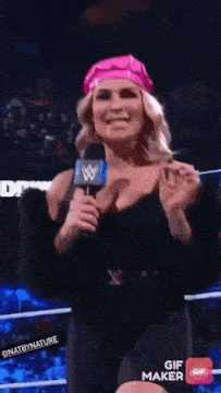 a woman in a pink hat is holding a microphone and smiling .