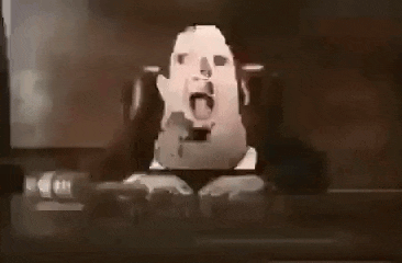 a man in a suit is sitting at a desk with his tongue out .