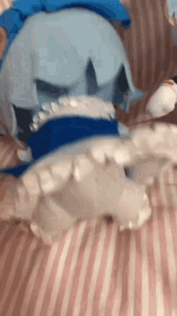a blue and white stuffed animal is laying on a striped bed .