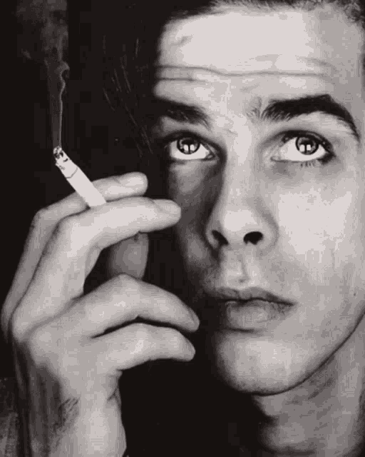a man smoking a cigarette with smoke coming out of it