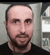 a man with a beard is wearing headphones and making a face .