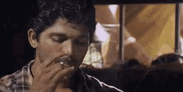 a man is smoking a cigarette and drinking a glass of beer .