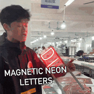 a man in a black jacket is holding a red neon sign that says magnetic neon letters