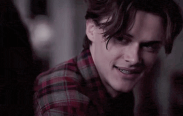 a close up of a young man wearing a plaid shirt and smiling .